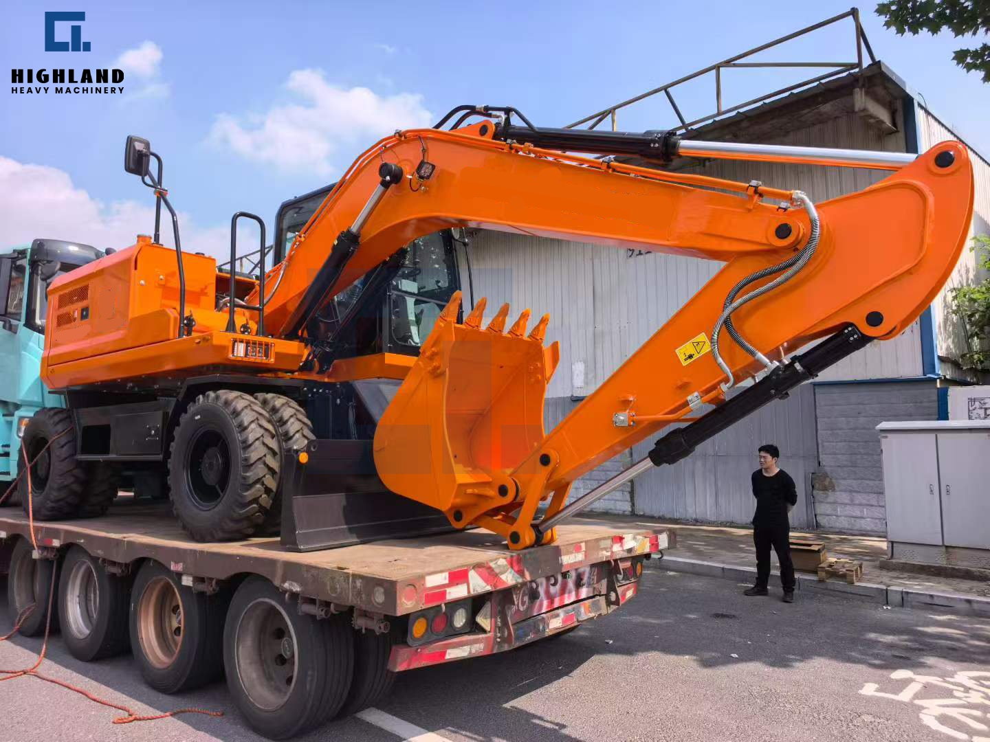 Orange large wheeled excavator being shipped by HIGHLAND HEAVY MACHINERY for construction projects