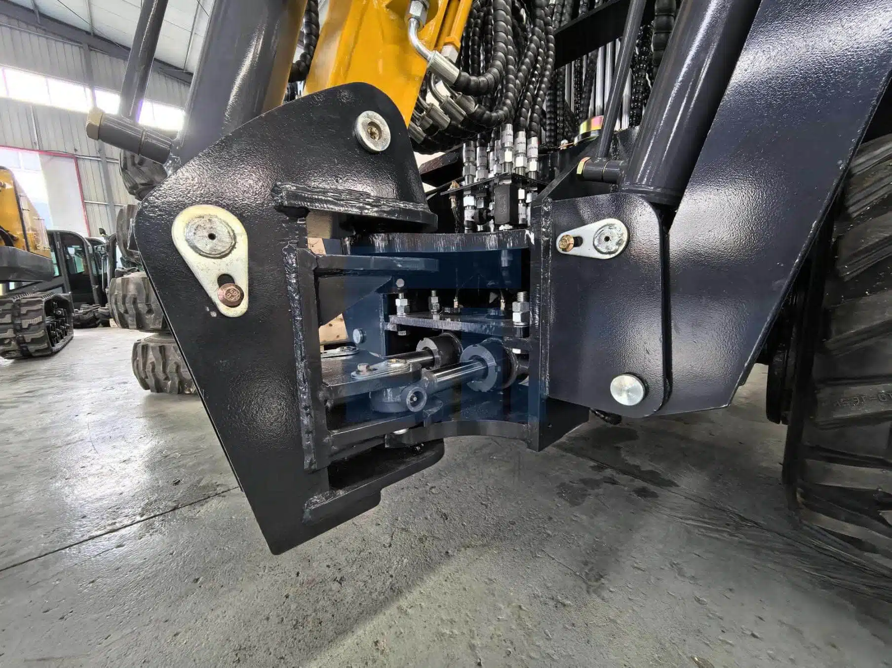 Close-up of HIGHLAND HEAVY MACHINERY HILT 50 backhoe loader wide-angle side swing mechanism, featuring heavy-duty pivot pins and welded construction for flexible rear excavation around walls and obstructions