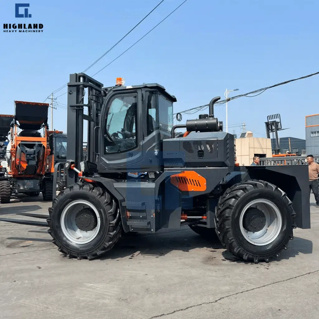 HIGHLAND HEAVY MACHINERY 5T articulated rough terrain forklift in dark grey with orange accents, enclosed cabin, and heavy-duty tires, parked at an industrial construction site, built for all-weather material handling.