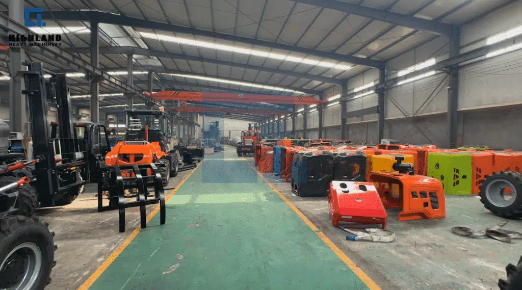 HIGHLAND HEAVY MACHINERY rough terrain forklift mass production workshop, featuring multiple orange and blue chassis units aligned along a green production floor, demonstrating a standardized industrial assembly process.
