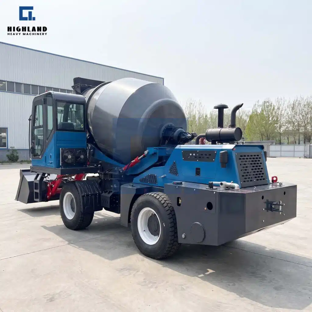 HIGHLAND HEAVY MACHINERY blue self loading concrete mixer truck rear side view showing the engine compartment, cooling grille, and exhaust pipe, parked outdoors in a factory yard.